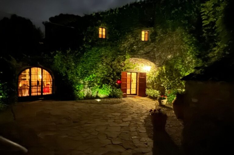 Night view of ivy-covered writers retreat villa with glowing entrance in Tuscany